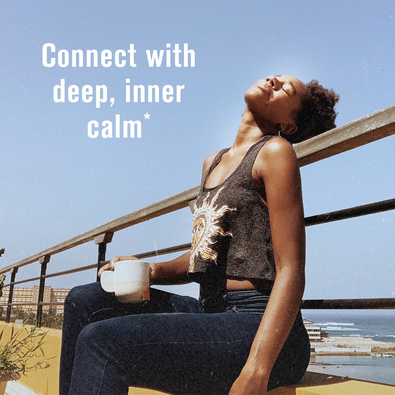 A woman sitting by the seashore relaxing with her cup of tea