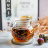 A pot of Numi Flowering Tea brewing in a glass tea pot