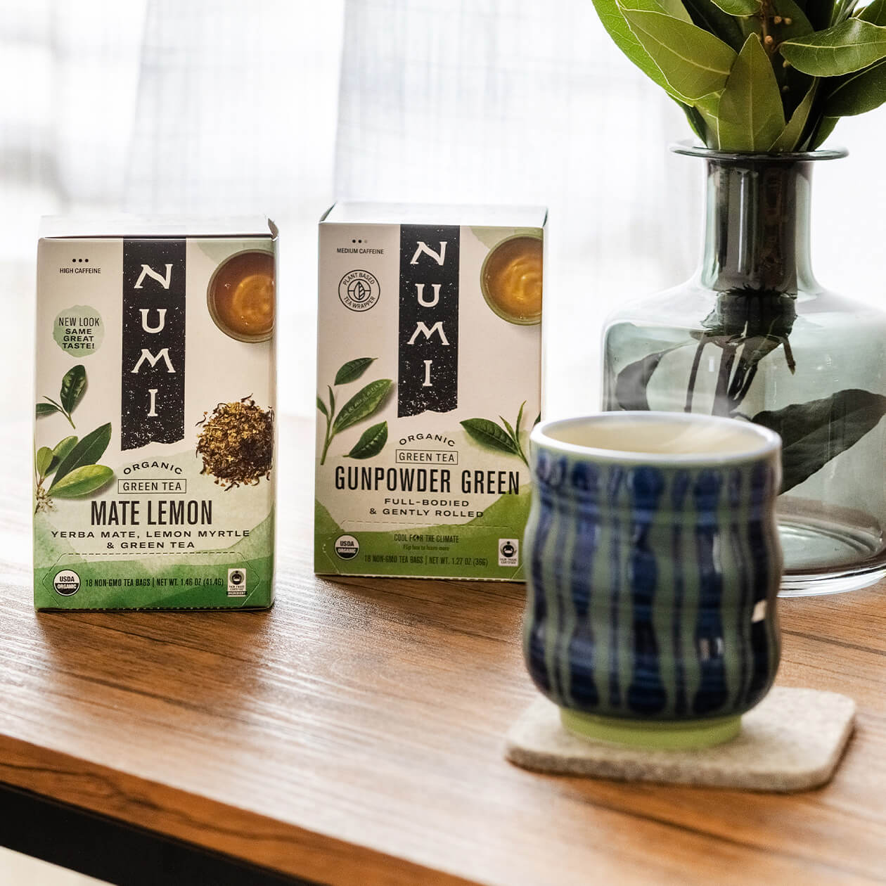 A box of Gunpowder Green tea on a desk with a hot cup of tea in the foreground