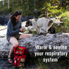 A woman takes a break from her hike to enjoy a hot cup of Immune Support with her dog