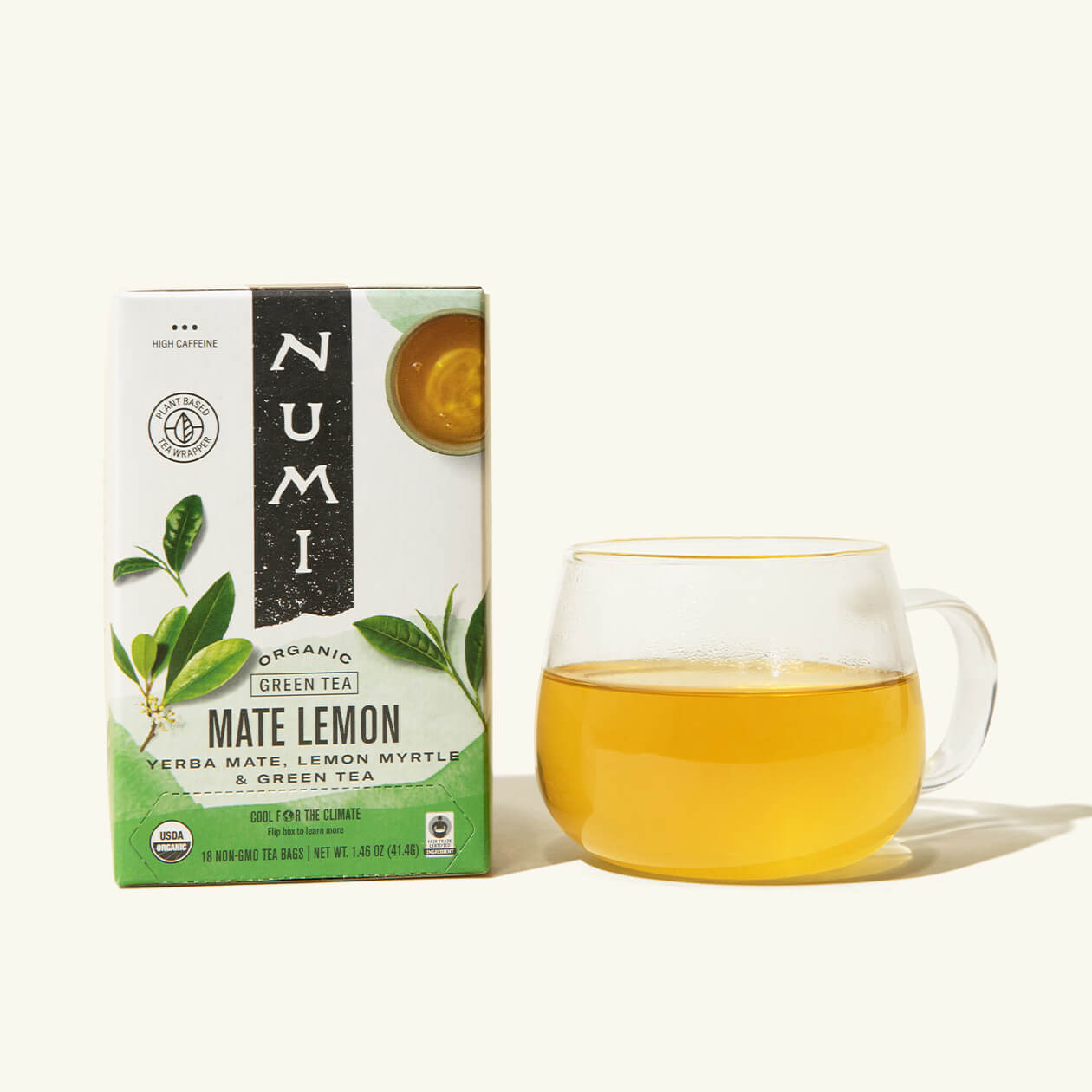 A box of Numi's Mate Lemon next to a brewed cup of tea in a clear cup