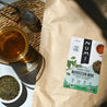 A bag of loose leaf Numi Moroccan Mint tea on a table with a cup of brewed loose leaf tea