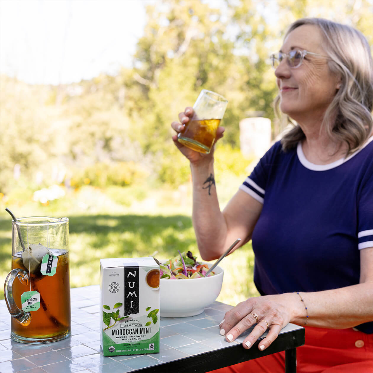 A woman enjoys an iced Numi Moroccan Mint tea with her healthy lunch