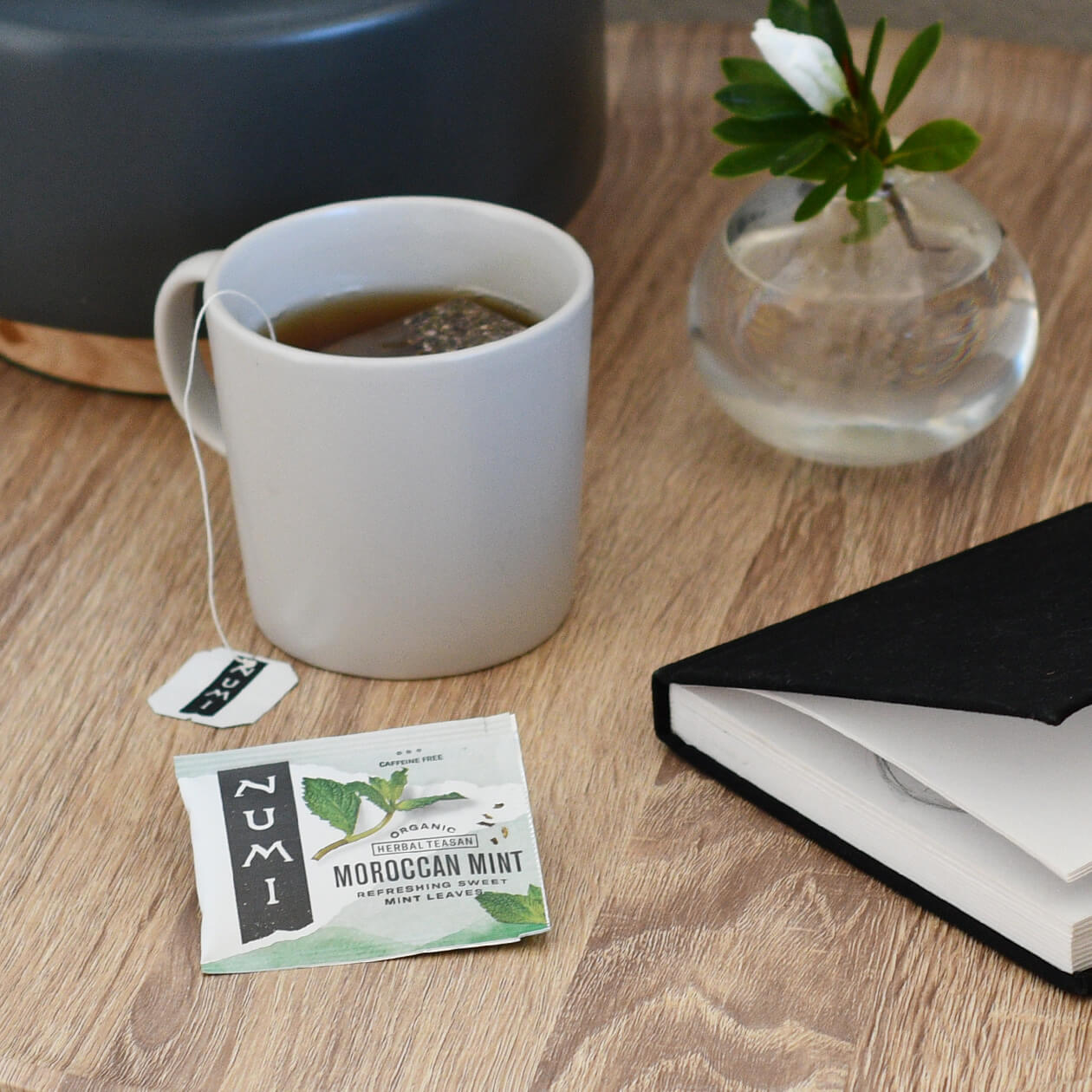 A cup of hot Numi Moroccan Mint tea on a bedside table