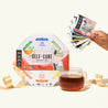 A Numi Self-care Sampler gift with a ribbon, a cup of brewed tea, and a person holding the variety of tea bags that come in this gift